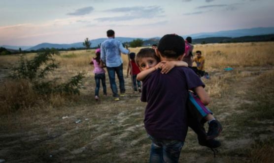 Un jove refugiat porta en braços al seu germà a prop d’Eidomeni (Grècia) | Foto: ACNUR / Andrew McConnell